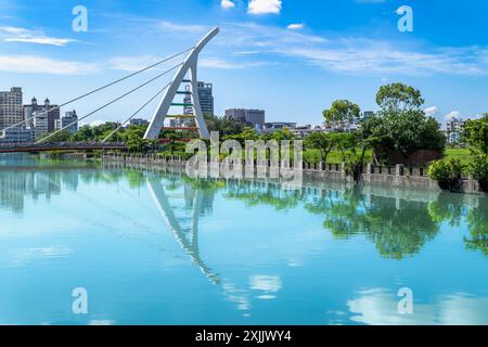 Il canale nel distretto di Annan, Tainan City, è pittoresco, con edifici moderni e ponti unici che si riflettono nelle calme acque blu. Foto Stock