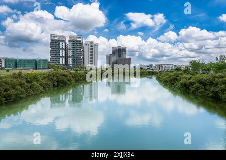 Il canale nel distretto di Annan, Tainan City, è pittoresco, con edifici moderni e ponti unici che si riflettono nelle calme acque blu. Foto Stock