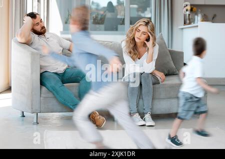 Mal di testa, genitori e bambini seduti sul divano con adhd, corsa e comportamento impulsivo con sfocatura del movimento a casa. Famiglia, madre e padre sul divano per Foto Stock