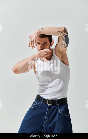 Bell'uomo caucasico vestito con sicurezza con una canotta bianca e jeans blu. Foto Stock