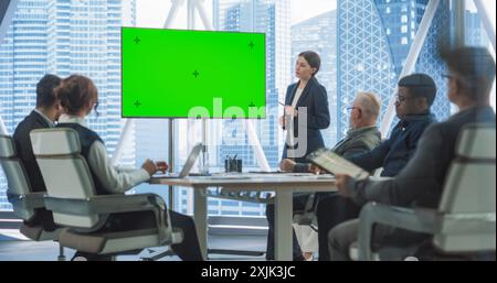 Presentazione della sala conferenze dell'ufficio: Una bella donna d'affari parla, utilizza un set TV Chroma Key Green Screen. Digital Entrepreneur presenta il prodotto e-Commerce durante l'incontro con diversi investitori del gruppo. Foto Stock