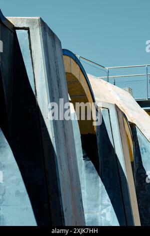 Primo piano di una moderna architettura industriale che mostra strutture in cemento con ombre e contrasto di luce contro un cielo limpido. Foto Stock