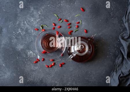 Tazza di tè alle erbe con bacche di goji fresche su tavola rustica Foto Stock