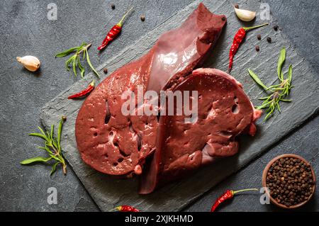 Carne cruda di fegato di manzo su bordo di pietra con timo e peperoni neri, calici di bestiame Foto Stock