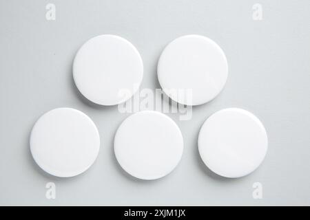 Badge bianchi vuoti su sfondo chiaro, disposizione piatta. Mockup per il design Foto Stock