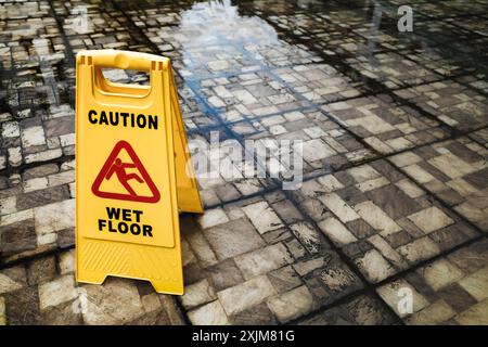 Cartello di avvertimento giallo su due lati per pavimenti bagnati posizionato in piedi su pavimenti esterni bagnati sporchi e bagnati Foto Stock