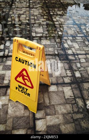 Cartello di segnalazione giallo su due lati per pavimenti bagnati posizionato su pavimenti esterni sporchi bagnati e allagati Foto Stock