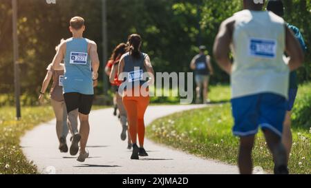 Ampia vista dei diversi partecipanti alla Maratona che gareggiano per il traguardo: Gruppo di persone che corrono attraverso il Park Health Trail e partecipano a una Maratona con dedizione Foto Stock