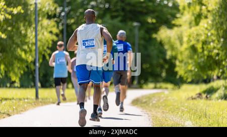 Vista posteriore dei diversi partecipanti alla Maratona che gareggiano in una gara per il traguardo: Gruppo di persone che corrono attraverso il Park Health Trail e partecipano a una Maratona con dedizione Foto Stock