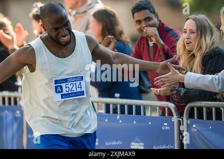 Marathon Audience applaude e applaude ai propri cari che partecipano alla gara: Black Athletic male Marathon Runner che dà un High Five a un'amica femminile che lo sostiene nel pubblico durante la corsa Foto Stock