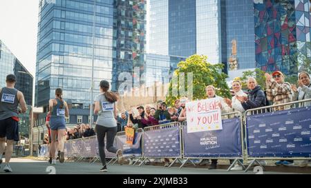 Vista posteriore: Diversi gruppi di Joggers maratonesi che gareggiano per il primo posto, correndo in un City Trail Audience applaudendo e applaudendo i loro cari che partecipano alla gara Foto Stock