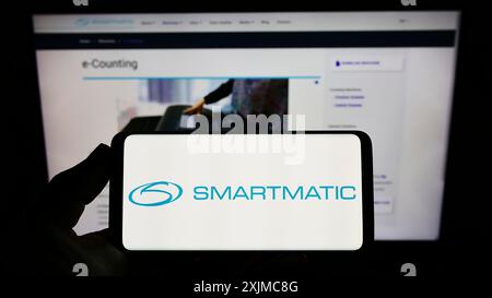 Stoccarda, Germania, 05-21-2022: Persona che possiede uno smartphone con logo della società del sistema di voto Smartmatic Corporation sullo schermo davanti al sito web. Foto Stock