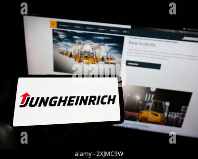 Stoccarda, Germania, 05-21-2022: Persona che possiede uno smartphone con il logo della società tedesca di ingegneria Jungheinrich AG sullo schermo davanti al sito web. Foto Stock