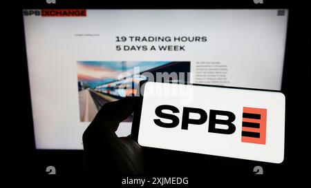 Stoccarda, Germania, 06-18-2022: Persona che detiene un cellulare con il logo della borsa SPB del mercato finanziario russo sullo schermo davanti all'azienda Foto Stock