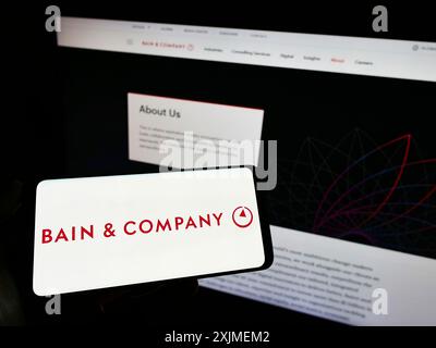 Stoccarda, Germania, 06-11-2022: Persona che detiene un telefono cellulare con il logo della società di consulenza americana Bain and Company Inc. Sullo schermo davanti al web Foto Stock