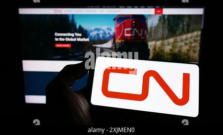 Stoccarda, Germania, 06-11-2022: Persona che tiene il cellulare con il logo della Canadian National Railway Company (CN) sullo schermo davanti alla pagina web aziendale. Foto Stock