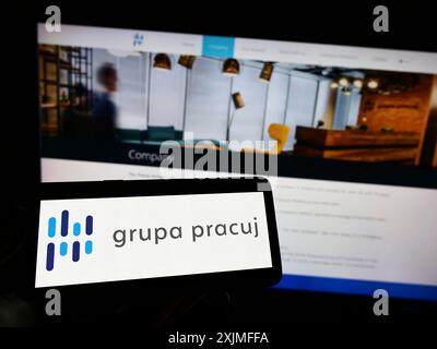 Stoccarda, Germania, 06-19-2022: Persona che detiene il cellulare con il logo della società polacca di reclutamento Grupa Pracuj SA sullo schermo davanti all’azienda Foto Stock