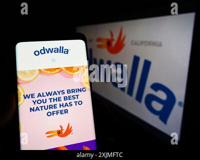 Stoccarda, Germania, 06-19-2022: Persona che detiene il cellulare con pagina web della società americana di bevande Odwalla sullo schermo davanti al logo aziendale. Concentrati Foto Stock