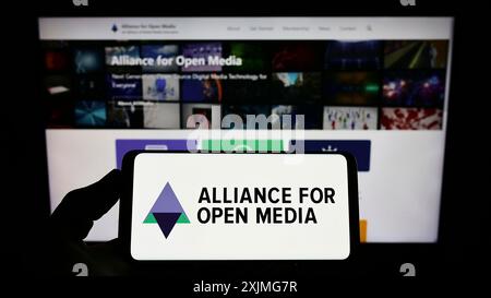 Stoccarda, Germania, 07-10-2022: Persona che possiede uno smartphone con il logo del consorzio Alliance for Open Media (AOMedia) sullo schermo di fronte al sito web. Foto Stock