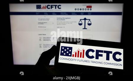 Stoccarda, Germania, 07-13-2022: Persona che possiede uno smartphone con il logo della US Commodity Futures Trading Commission (CFTC) sullo schermo davanti al sito web. Foto Stock