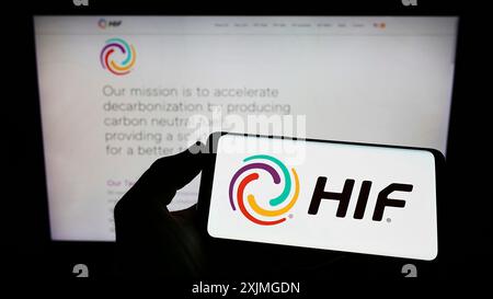 Stoccarda, Germania, 07-10-2022: Persona che detiene un telefono cellulare con il logo della società cilena di carburante elettronico HIF Global sullo schermo di fronte alla pagina web aziendale. Foto Stock