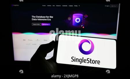 Stoccarda, Germania, 07-16-2022: Persona che detiene il cellulare con il logo della società di software americana SingleStore Inc. Sullo schermo davanti all'azienda Foto Stock