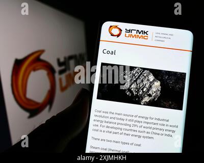 Stoccarda, Germania, 07-24-2022: Persona che tiene il cellulare con pagina web della società mineraria e metallurgica degli Urali (UMMC) sullo schermo con logo. Concentrati su Foto Stock