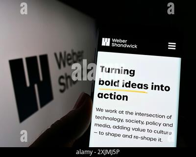 Stoccarda, Germania, 07-30-2022: Persona che detiene il cellulare con pagina web della società di comunicazioni di marketing Weber Shandwick sullo schermo con il logo. Concentrati Foto Stock