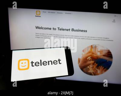 Stoccarda, Germania, 07-30-2022: Persona che detiene il cellulare con il logo della società belga Telenet Group Holding NV sullo schermo davanti all’azienda Foto Stock