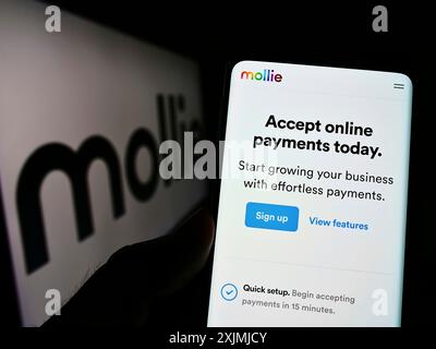 Stoccarda, Germania, 07-31-2022: Persona che detiene uno smartphone con pagina web della società olandese di pagamenti Mollie B.V., sullo schermo davanti al logo. Concentrati su Foto Stock