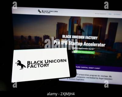 Stoccarda, Germania, 07-31-2022: Persona che detiene un telefono cellulare con il logo della società di capitali di rischio statunitense Black Unicorn Factory sullo schermo davanti al web Foto Stock