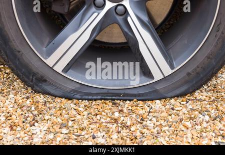 Pneumatico sgonfio su una ruota di un'auto. Primo piano di una ruota di un'auto con uno pneumatico sgonfio, foratura dello pneumatico. Parte di una serie di foto che raffigurano la sostituzione di uno pneumatico forato Foto Stock