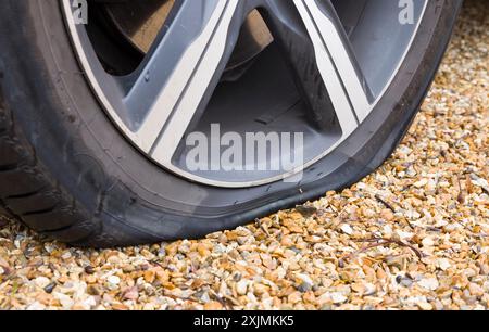 Pneumatico sgonfio su una ruota di un'auto. Primo piano di una ruota di un'auto con uno pneumatico sgonfio, foratura dello pneumatico. Parte di una serie di foto che raffigurano la sostituzione di uno pneumatico forato Foto Stock