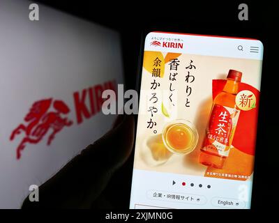 Telefono cellulare con sito web della Japanese Kirin Brewery Company Limited sullo schermo davanti al logo. Messa a fuoco al centro del display del telefono Foto Stock