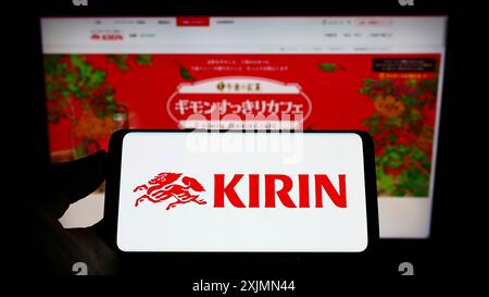 Telefono cellulare con logo della Japanese Kirin Brewery Company Limited sullo schermo di fronte alla pagina Web aziendale. Mettere a fuoco il display del telefono Foto Stock