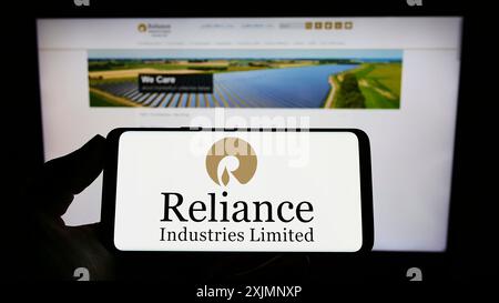 Stoccarda, Germania, 09-22-2022: Persona che detiene il cellulare con il logo della società indiana Reliance Industries Limited sullo schermo davanti all'azienda Foto Stock