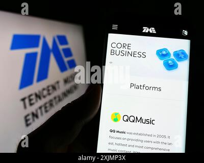 Stoccarda, Germania, 09-25-2022: Persona che detiene il cellulare con pagina web della società Tencent Music Entertainment Group sullo schermo davanti al logo. Concentrati Foto Stock