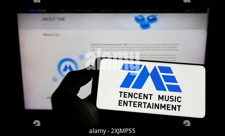 Stoccarda, Germania, 09-25-2022: Persona che detiene il cellulare con il logo della società Tencent Music Entertainment Group sullo schermo davanti al business web Foto Stock