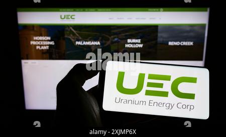 Stoccarda, Germania, 09-25-2022: Persona che detiene il cellulare con il logo della società mineraria statunitense Uranium Energy Corp. (UEC) sullo schermo di fronte a Foto Stock