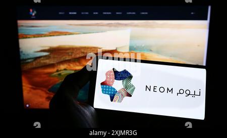 Stoccarda, Germania, 10-01-2022: Persona che tiene un telefono cellulare con il logo dello sviluppatore di proprietà saudita NEOM Company sullo schermo davanti al web Foto Stock