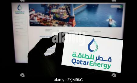 Stoccarda, Germania, 10-09-2022: Persona che detiene un cellulare con il logo della società petrolifera del Qatar QatarEnergy sullo schermo di fronte alla pagina web aziendale. Foto Stock