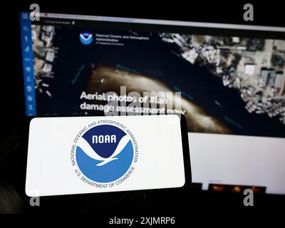 Stoccarda, Germania, 10-09-2022: Persona con smartphone con logo della National Oceanic and Atmospheric Administration (NOAA) sullo schermo con Web Foto Stock