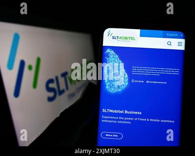 Stoccarda, Germania, 10-15-2022: Persona che detiene il cellulare con pagina web della società di telecomunicazioni SLT-MOBITEL sullo schermo davanti al logo. Concentrati su Foto Stock