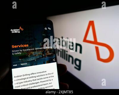 Stoccarda, Germania, 10-18-2022: Persona che detiene il cellulare con pagina web dell'azienda saudita Arabian Drilling Company (ADC) sullo schermo con logo. Concentrati su Foto Stock