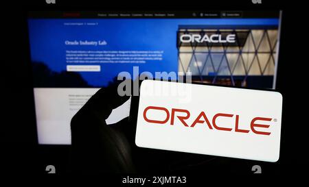 Stoccarda, Germania, 10-21-2022: Persona che detiene un cellulare con il logo della società tecnologica statunitense Oracle Corporation sullo schermo davanti all'azienda Foto Stock