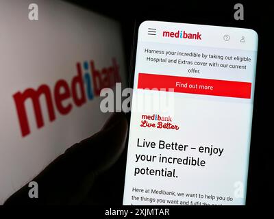 Stoccarda, Germania, 10-17-2022: Persona che detiene cellulare con pagina web della compagnia di assicurazione sanitaria Medibank Private Limited su schermo con logo. Concentrati Foto Stock