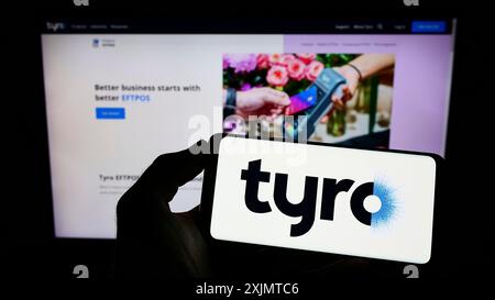 Stoccarda, Germania, 24-10-2022: Persona che detiene il cellulare con il logo della società australiana Tyro Payments Limited sullo schermo davanti alla pagina web. Foto Stock