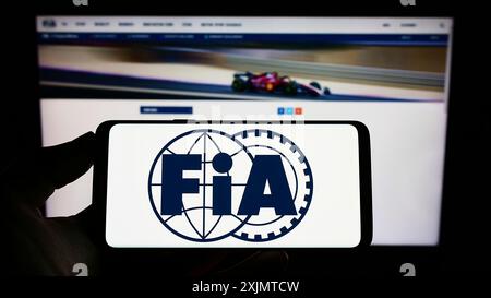 Stoccarda, Germania, 10-24-2022: Persona che tiene il cellulare con il logo della Federazione Internazionale dell'automobile (FIA) sullo schermo davanti alla pagina web. Concentrati Foto Stock