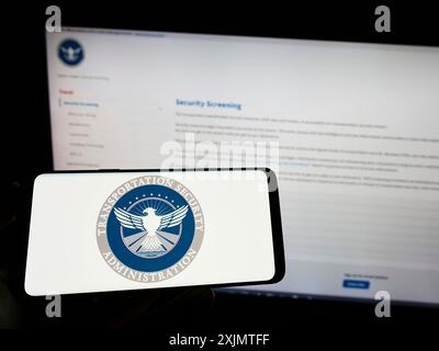 Stoccarda, Germania, 10-24-2022: Persona che tiene un telefono cellulare con il sigillo della Transportation Security Administration (TSA) sullo schermo davanti alla pagina web. Foto Stock