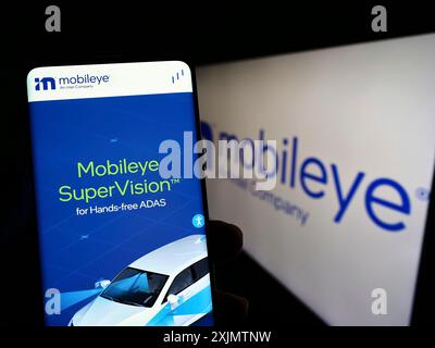 Stoccarda, Germania, 10-23-2022: Persona che detiene il cellulare con il sito web della società di guida autonoma israeliana Mobileye sullo schermo davanti al logo. Foto Stock